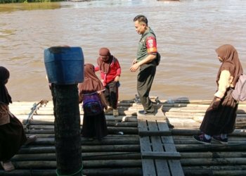 Hanya Ada Jalur Air, Babinsa Bantu Anak Sekolah Seberangi Sungai