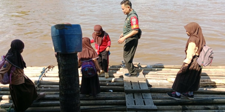 Hanya Ada Jalur Air, Babinsa Bantu Anak Sekolah Seberangi Sungai